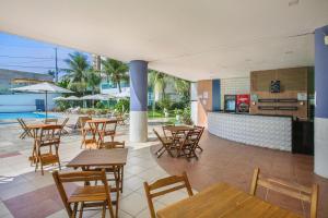 a restaurant with wooden tables and chairs and a pool at Mar de Ponta Negra in Natal