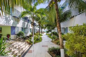 a palm tree next to a building with a walkway at Mar de Ponta Negra in Natal