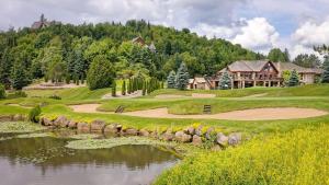 a golf course with a house and a pond at Log cabin with SPA, pool, and small beach in Mont-Tremblant