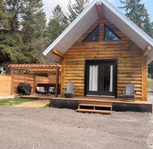a log cabin with two chairs and a table at Log cabin with SPA, pool, and small beach in Mont-Tremblant
