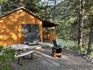 a small cabin with a grill and a chair on a deck at Doug's Emporium and Riverside Cabins in Hedley