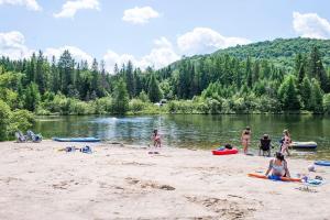 a group of people on a beach near a lake at Log cabin with SPA, pool, and small beach in Mont-Tremblant