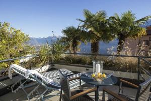 a patio with a table and chairs on a balcony at Hotel Barca Blu in Orselina