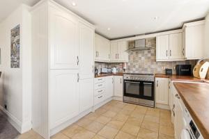a kitchen with white cabinets and a stove top oven at Ghyllstead - North East Escapes in Glanton +29 photos