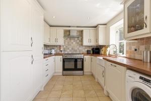 a kitchen with white cabinets and a stove top oven at Ghyllstead - North East Escapes in Glanton