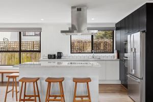 a kitchen with a white counter and some stools at Chic coastal living in Anglesea
