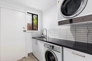 a kitchen with a washing machine and a sink at Chic coastal living in Anglesea