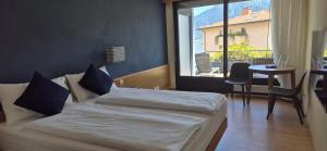 a bedroom with two beds and a table and a window at Hotel Barca Blu in Orselina