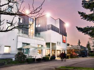a white building with people walking in front of it at ibis Nantes Saint Herblain in Saint-Herblain