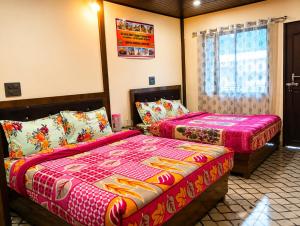 a bedroom with two beds and a window at Trinetra Himalayan Stay in Phata