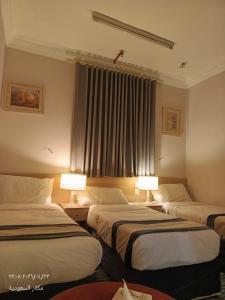 a hotel room with two beds and two lamps at فندق سكب الأصيل in An Naqāʼ +5 photos
