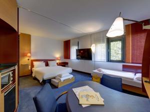 a hotel room with two beds and a table and chairs at Novotel Suites München Parkstadt Schwabing in Munich +85 photos