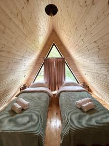 two beds in a triangular room with a window at Cottage GORDA Kazbegi in Akhalts'ikhe