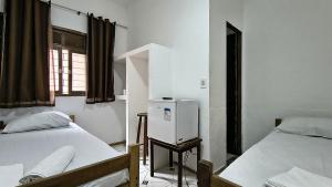 a room with two beds and a refrigerator at Hotel Silveira in Guarapari