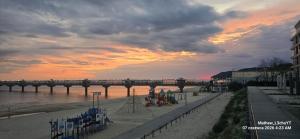 a bridge over the water with a beach at sunset at Skarb Morza in Międzyzdroje