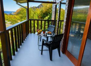 a table and chair on a balcony with a view of the ocean at Blue Sky Apartment in Soufrière