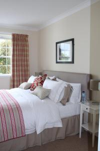 a bedroom with a bed with white sheets and a window at Skerrols House in Bridgend
