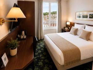 a hotel room with a large bed and a window at Mercure Lourdes Impérial in Lourdes