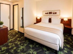 a hotel room with a large bed and a bathroom at Mercure Lourdes Impérial in Lourdes