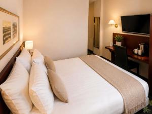 a hotel room with a bed with pillows and a desk at Mercure Lourdes Impérial in Lourdes