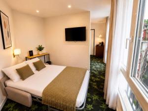 a hotel room with a bed and a flat screen tv at Mercure Lourdes Impérial in Lourdes +56 photos