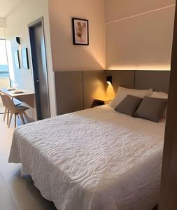 a bedroom with a large white bed and a desk at 818 - Standard Premium in Uberlândia