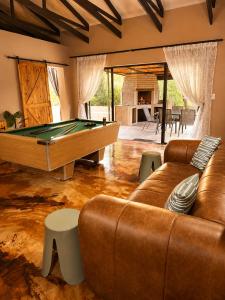 a living room with a pool table and leather couches at Wonderviews Hedgehog in Marloth Park