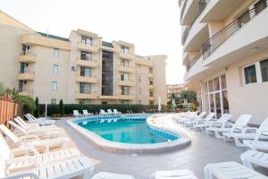 una piscina con sillas blancas y un edificio en Hotel Veris, en Sunny Beach