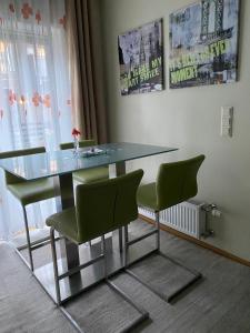 a dining table with green chairs in a room at SV Appartamenty in Horten