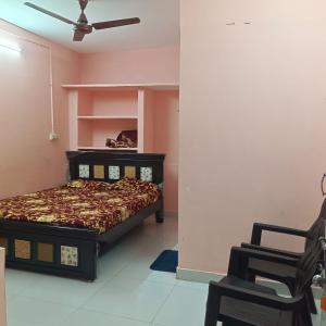 a bedroom with a bed and two chairs in it at Jyothi swaroop bhakta nivas in Tirupati +2 photos
