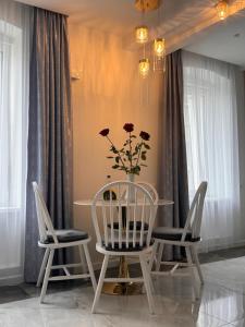 a table with two chairs and a vase with flowers at Centro Apartamentai in Plungė