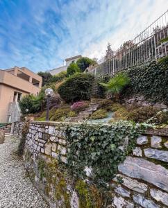 a stone wall with ivy on it next to a building at NEW Larioview suites in Argegno
