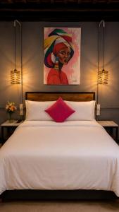 a bedroom with a white bed with a painting on the wall at Maloka Boutique Centro Histórico in Cartagena de Indias