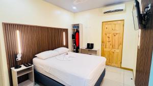 a bedroom with a white bed and a wooden door at Hotel Costa del Sol in Puerto Limón