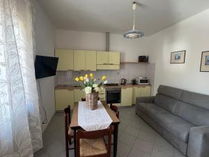 a kitchen and a living room with a table and a couch at Appartamento Marisa2 a soli 200mt dal mare e vista mare in Fetovaia