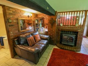 a living room with a leather couch and a fireplace at Severn Bank Lodge in Shrawley