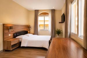 a bedroom with a white bed and a window at Aparthotel Madeleine in Antananarivo