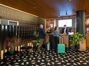 a lobby with people standing at a counter with luggage at Novotel Wien City in Vienna