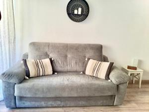 a couch in a living room with a clock on the wall at BoHémian Studio in Sète Center in Sète
