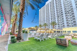 a lawn with chairs and palm trees and a building at Collection O Las Vegas in Las Vegas