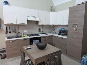 a kitchen with white cabinets and a wooden table at Pasithea House in Marzamemi