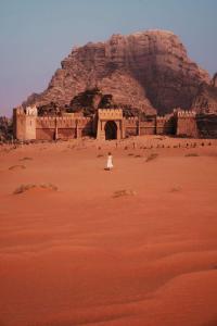 a person sitting in front of a building in the desert at مخيم سياحي in Disah