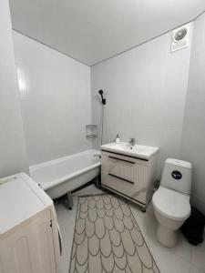 a white bathroom with a toilet and a sink at Дом in Almaty