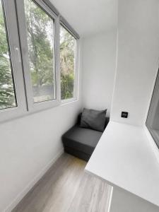 a room with a black couch and two windows at Дом in Almaty