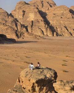 two people sitting on a rock in the desert at مخيم سياحي in Disah