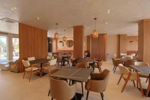 a restaurant with tables and chairs and windows at Hotel Landi in Ksamil