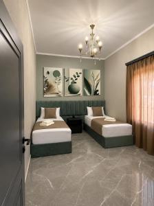 a bedroom with two beds and a chandelier at Yolyans Hotel in Goris