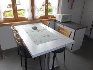 eine Küche mit einem weißen Tisch mit Stühlen und einer Mikrowelle in der Unterkunft Luxurious Chalet in Habkern with Private Garden in Habkern