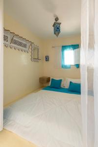 a bedroom with a large white bed with blue pillows at Dar Ahlem Djerba in El Guecheïne +19 photos