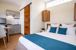 a bedroom with a blue and white bed and a kitchen at Aparthotel Madeleine in Antananarivo +6 photos